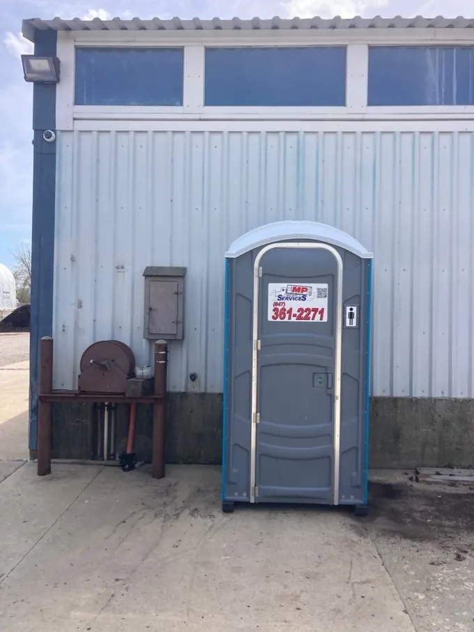 A gray MP Sanitation standard portable toilet placed and serviced on a Lake County job site